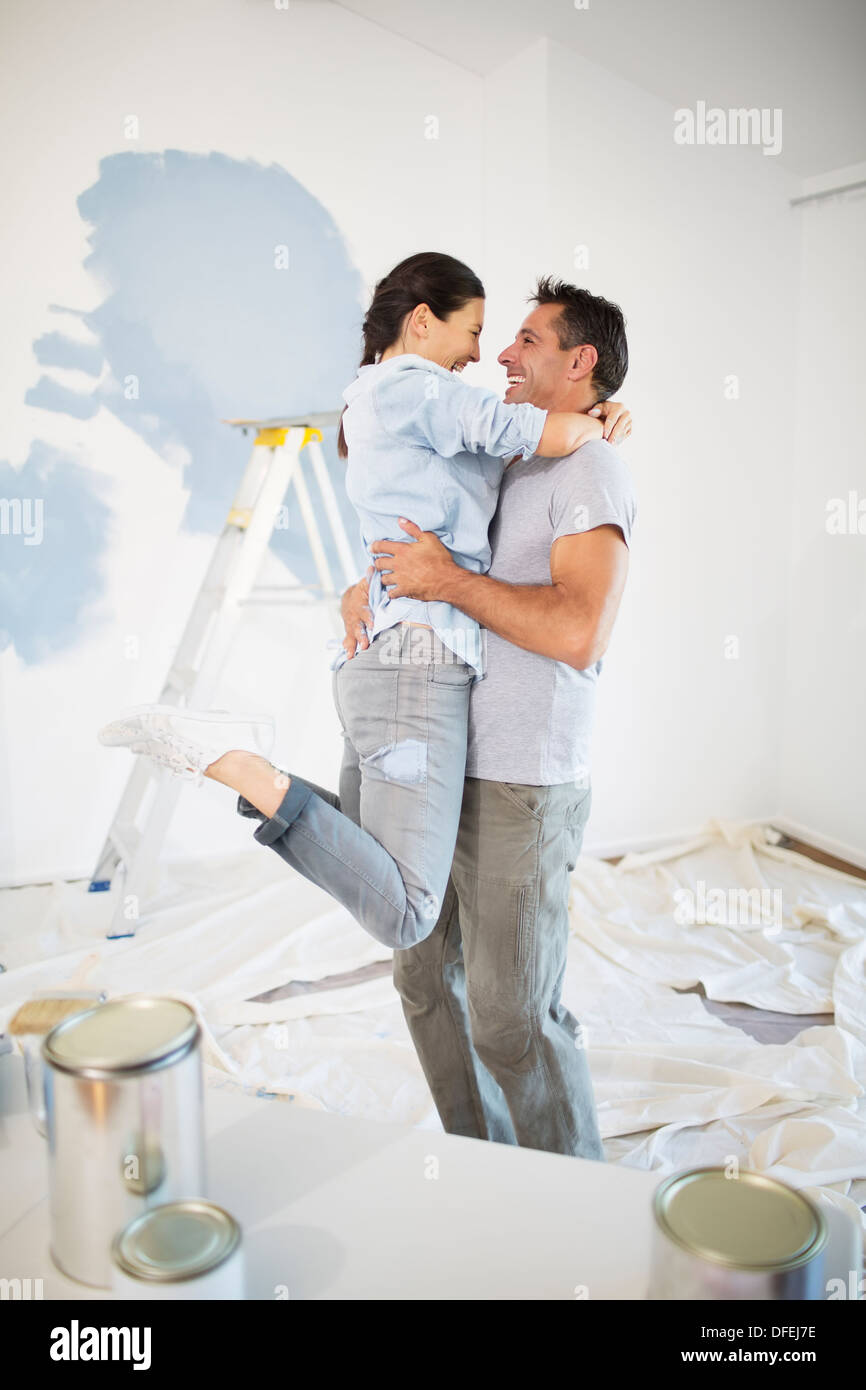 Couple hugging among paint supplies Stock Photo