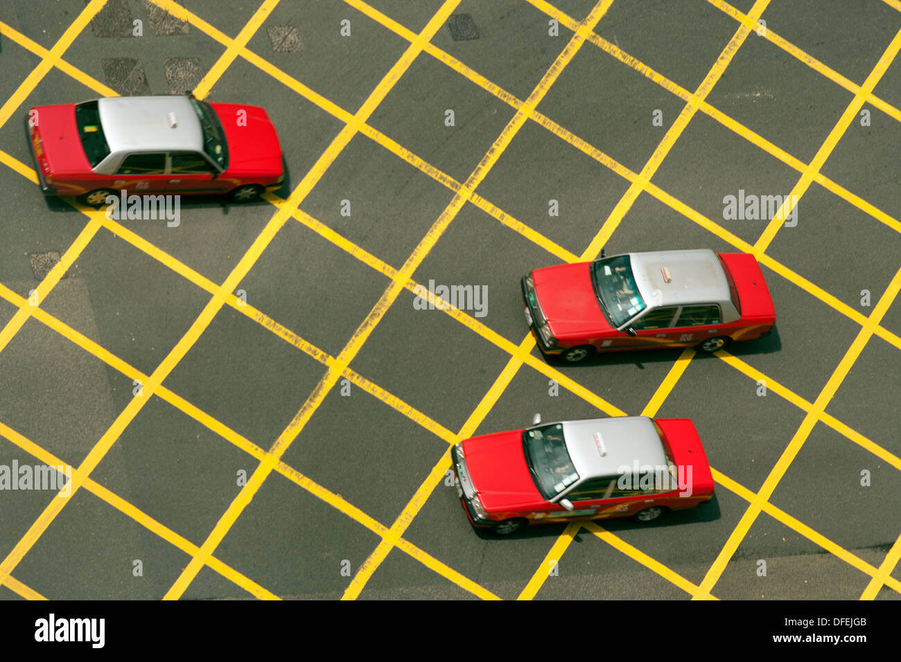 Three taxis seen from above crossing a yellow grid of an intersection, Hong Kong , China Stock Photo