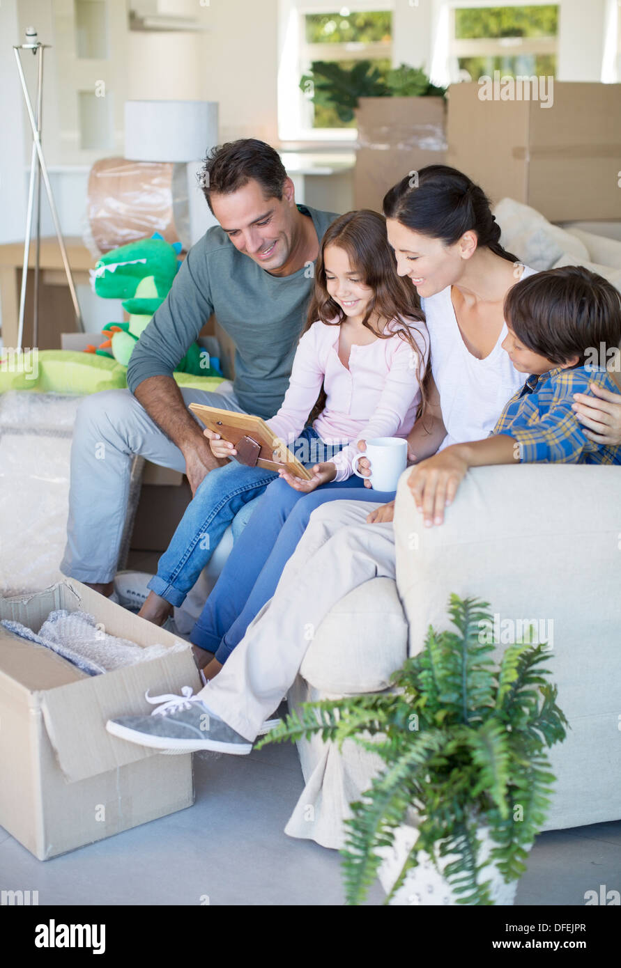 Family looking at picture frame on sofa among cardboard boxes Stock Photo