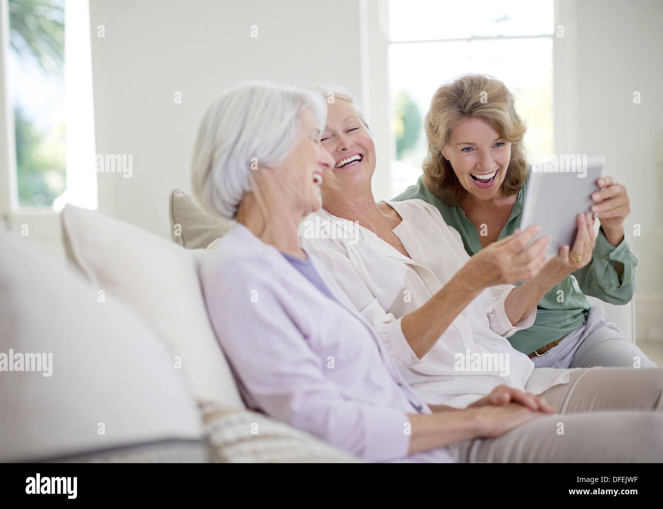 Older women using digital tablet on sofa Stock Photo