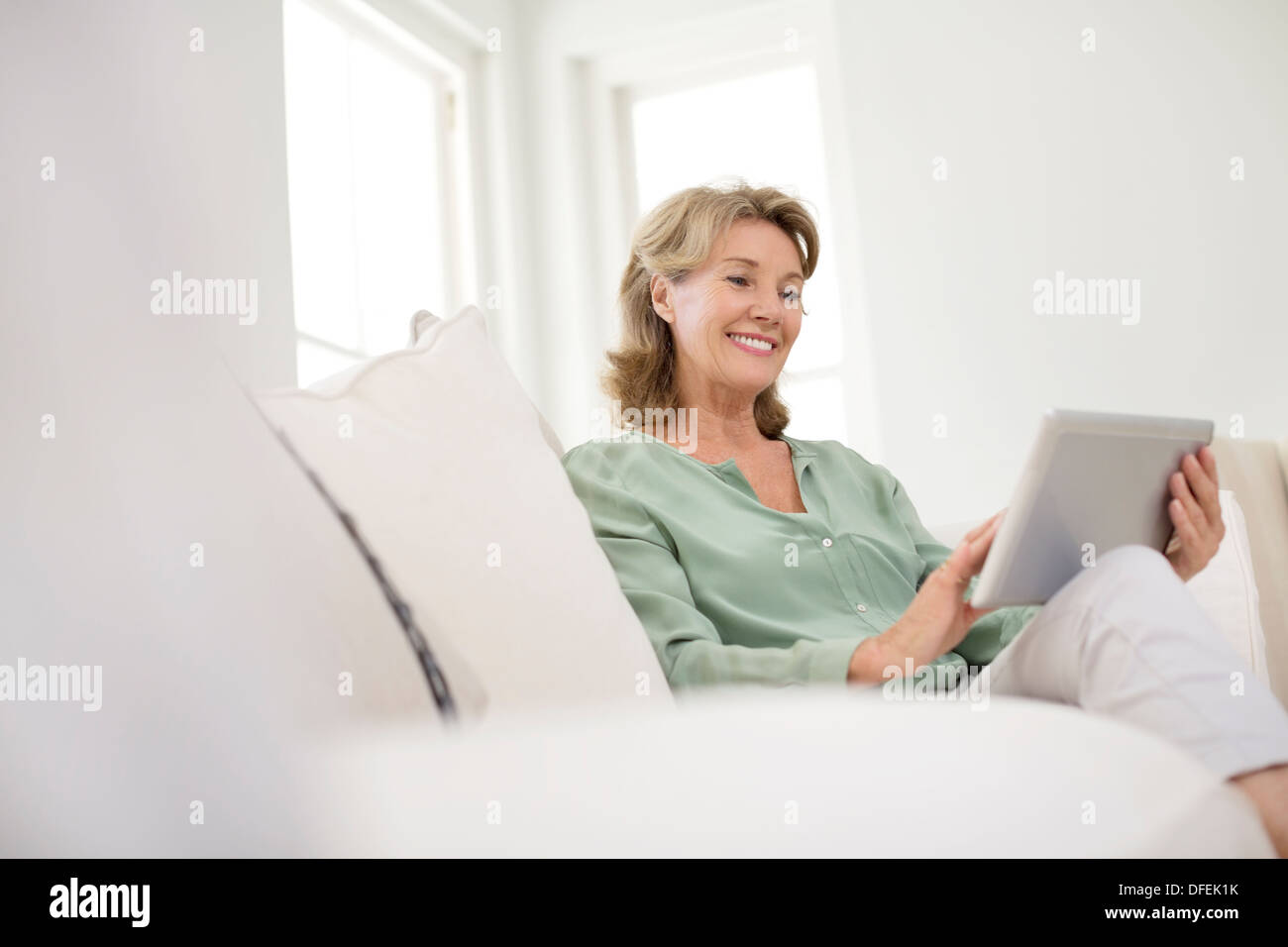 Senior woman using digital tablet on sofa Stock Photo