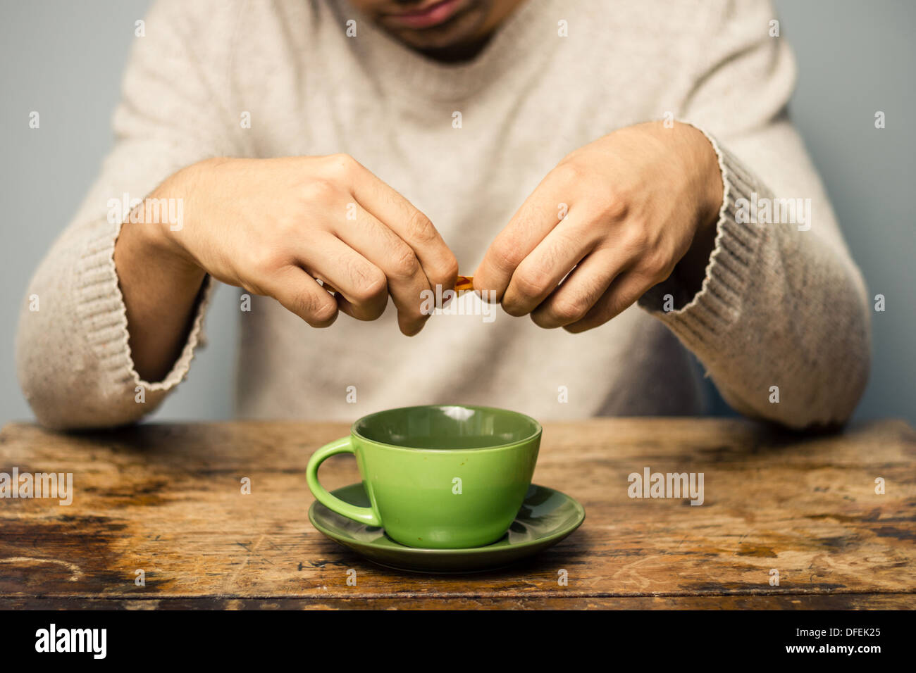 Young man in cafe is adding sugar to his coffee Stock Photo