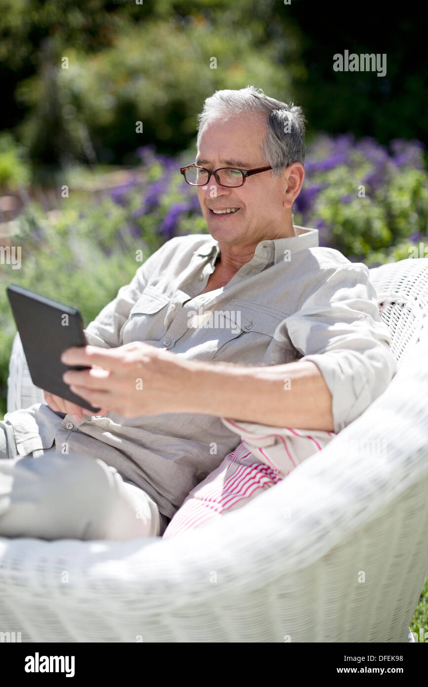 Senior man using digital tablet in armchair Stock Photo