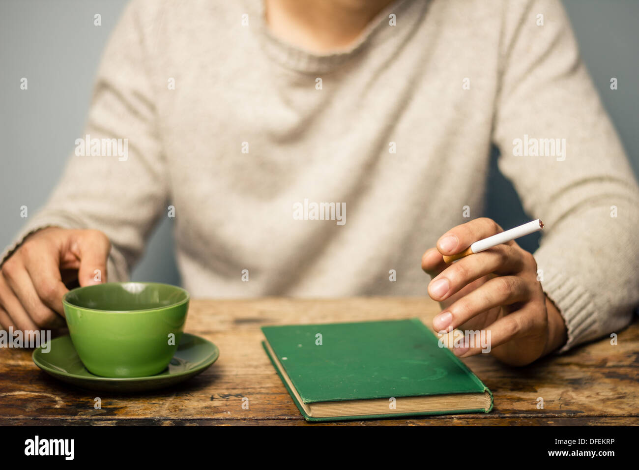 Man smoking cigarette and drinking coffee after reading a book Stock