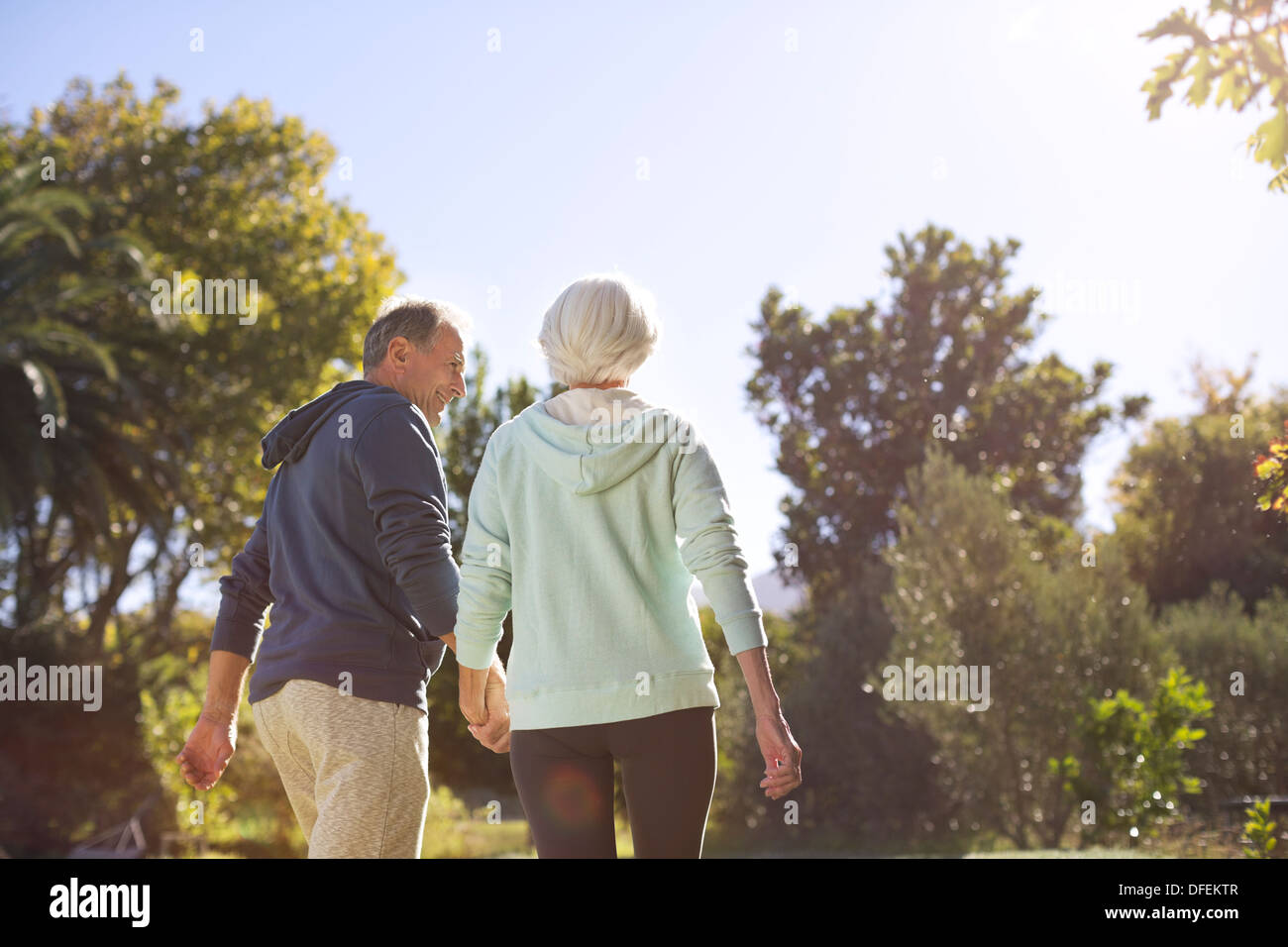 Senior couple holding hands and walking in park Stock Photo