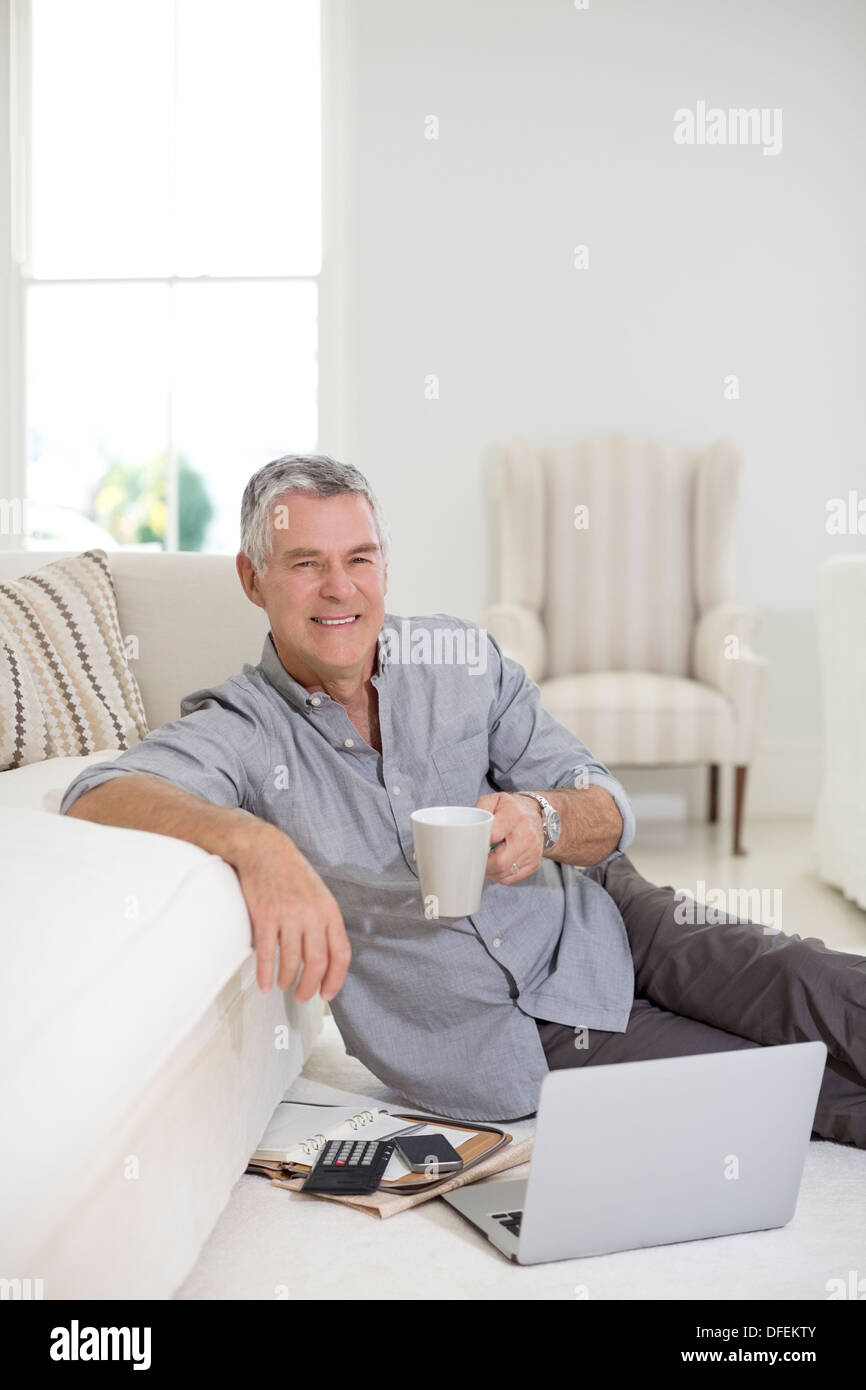 Senior man using laptop on living room floor Stock Photo