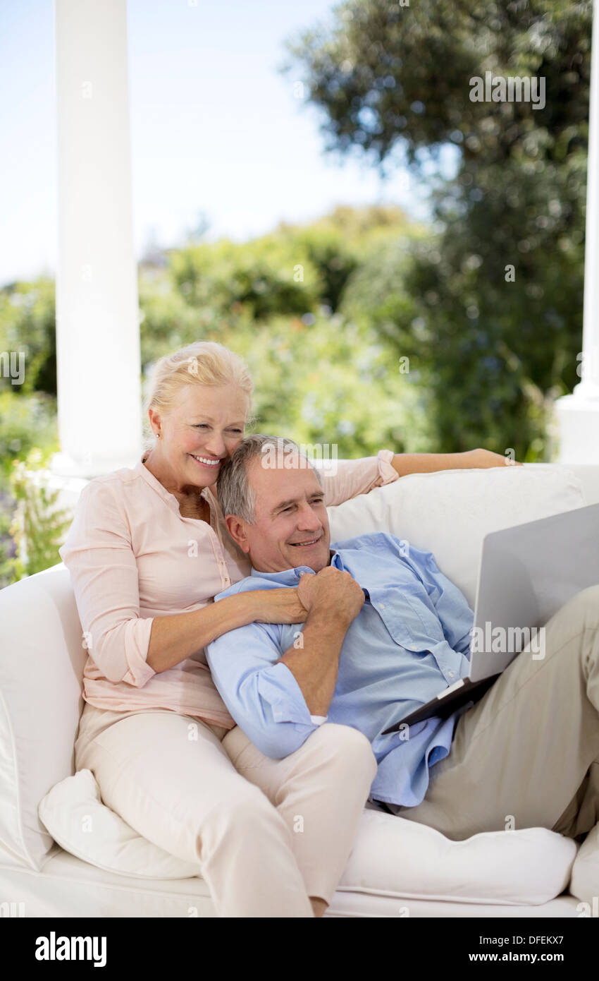 Senior couple using laptop on patio sofa Stock Photo