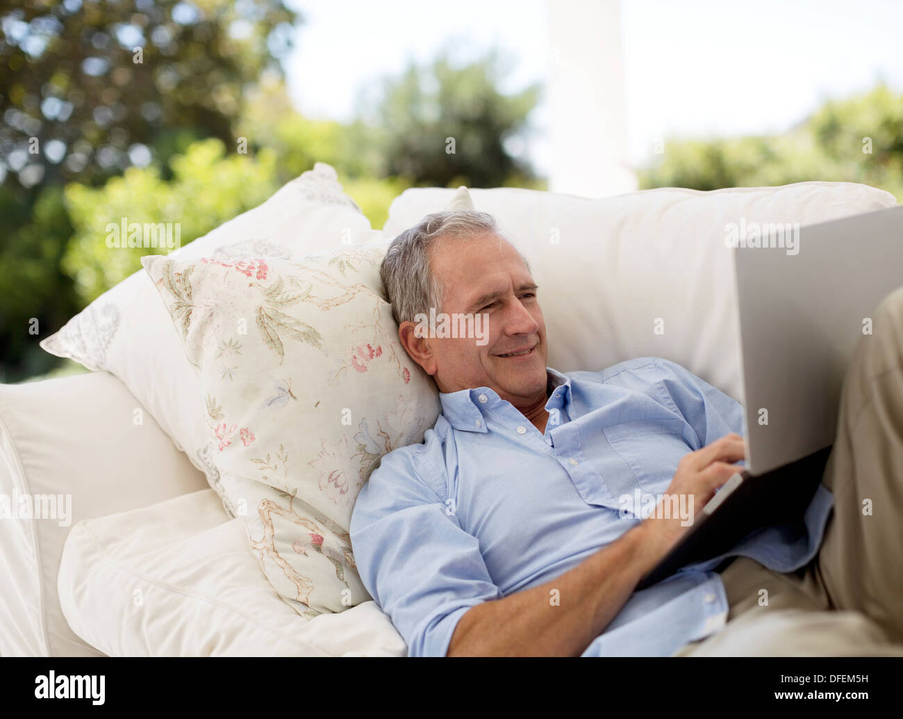 Senior man using laptop on patio sofa Stock Photo