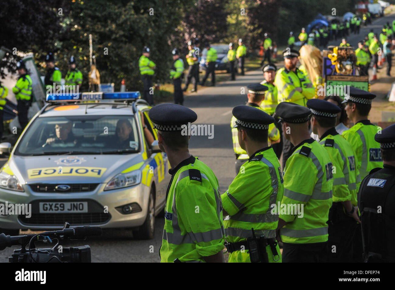 Police Officers line the roadside with Police car on left. Anti fracking protests at Balcombe, West Sussex,UK Stock Photo