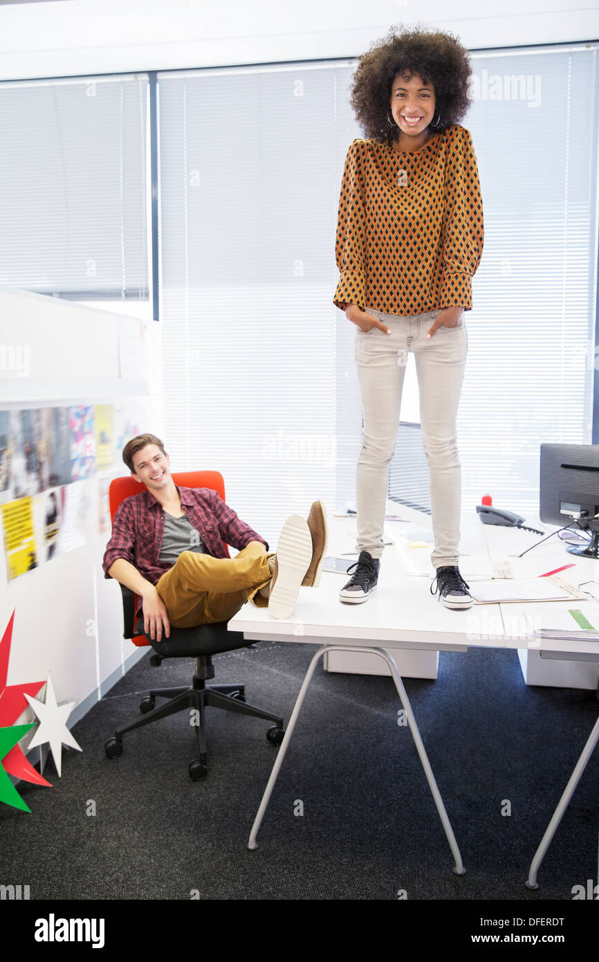 Business woman standing on table in office Stock Photo