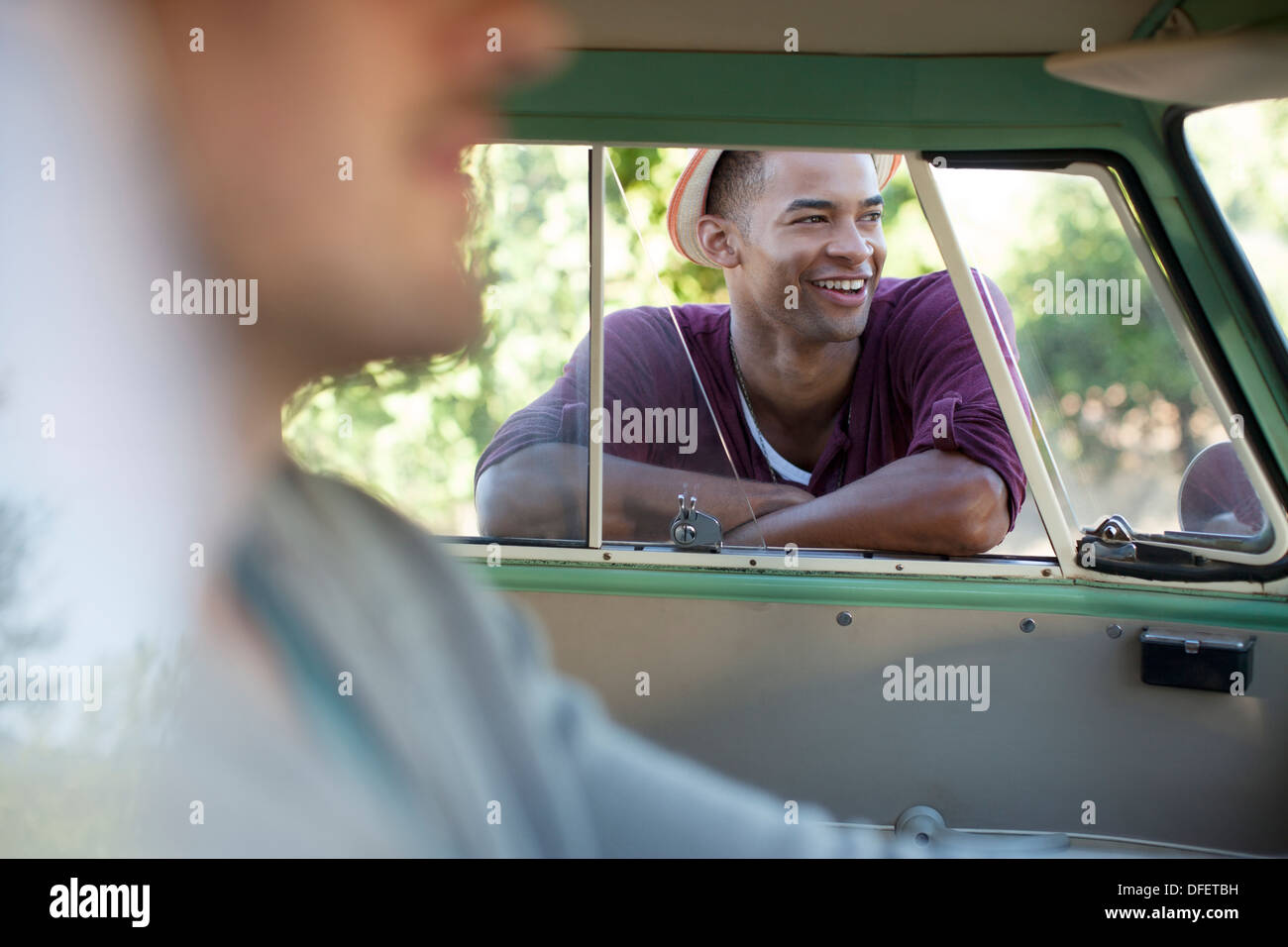 Smiling man standing at camper van window Stock Photo