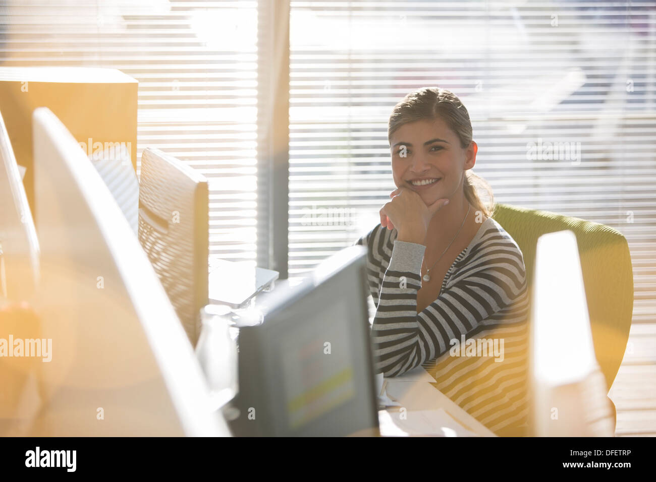 Portrait of smiling businesswoman at desk Stock Photo