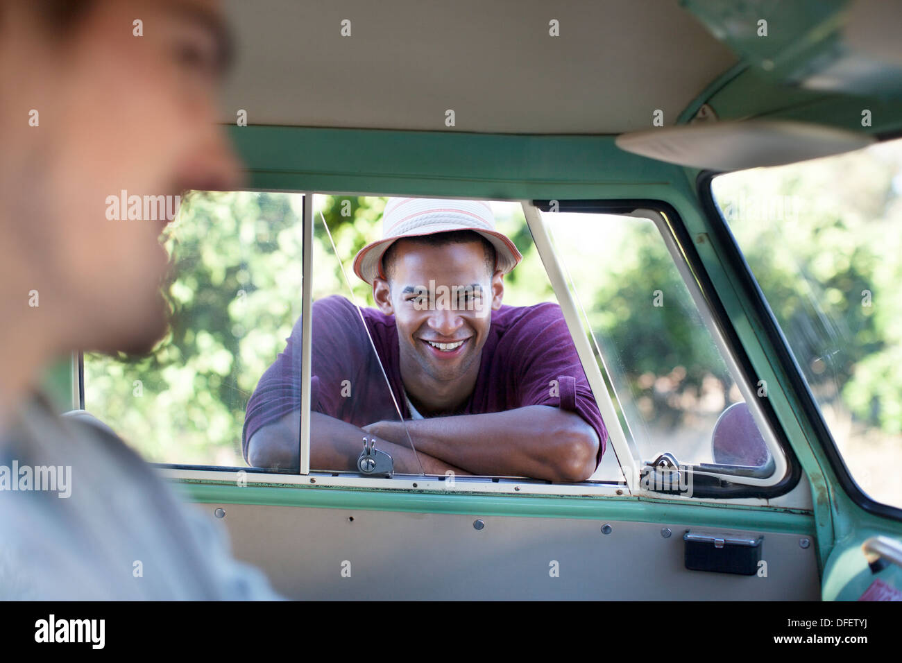 Smiling man leaning on camper van window Stock Photo