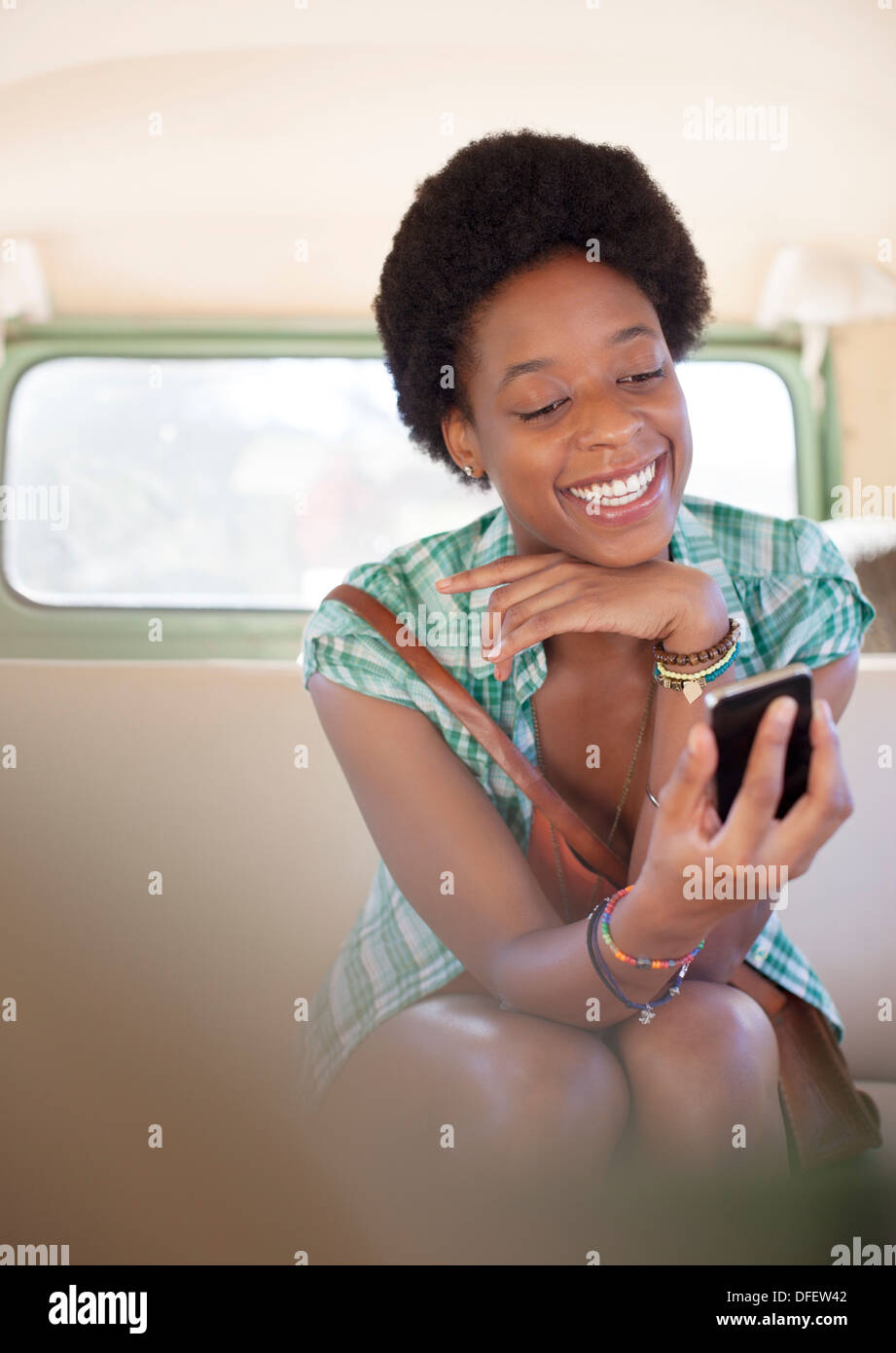 Woman using cell phone in back seat of camper van Stock Photo