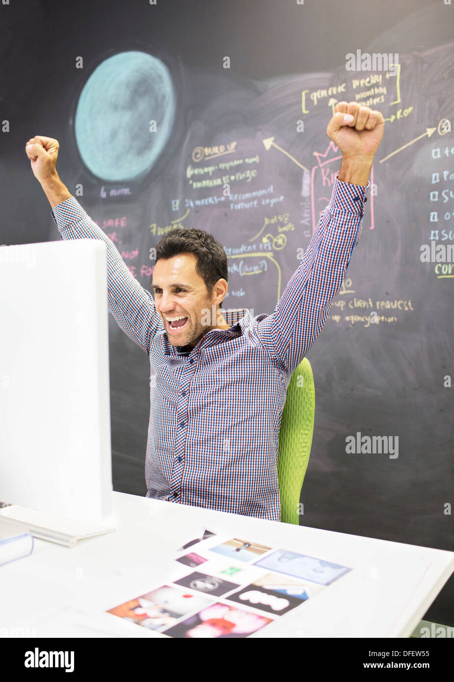 Businessman cheering at desk in office Stock Photo