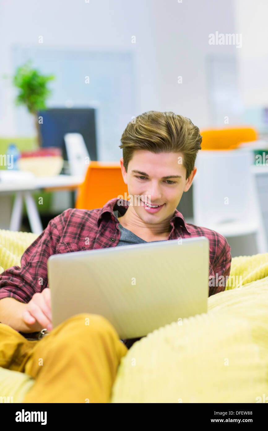 Businessman using laptop in bean bag chair in office Stock Photo