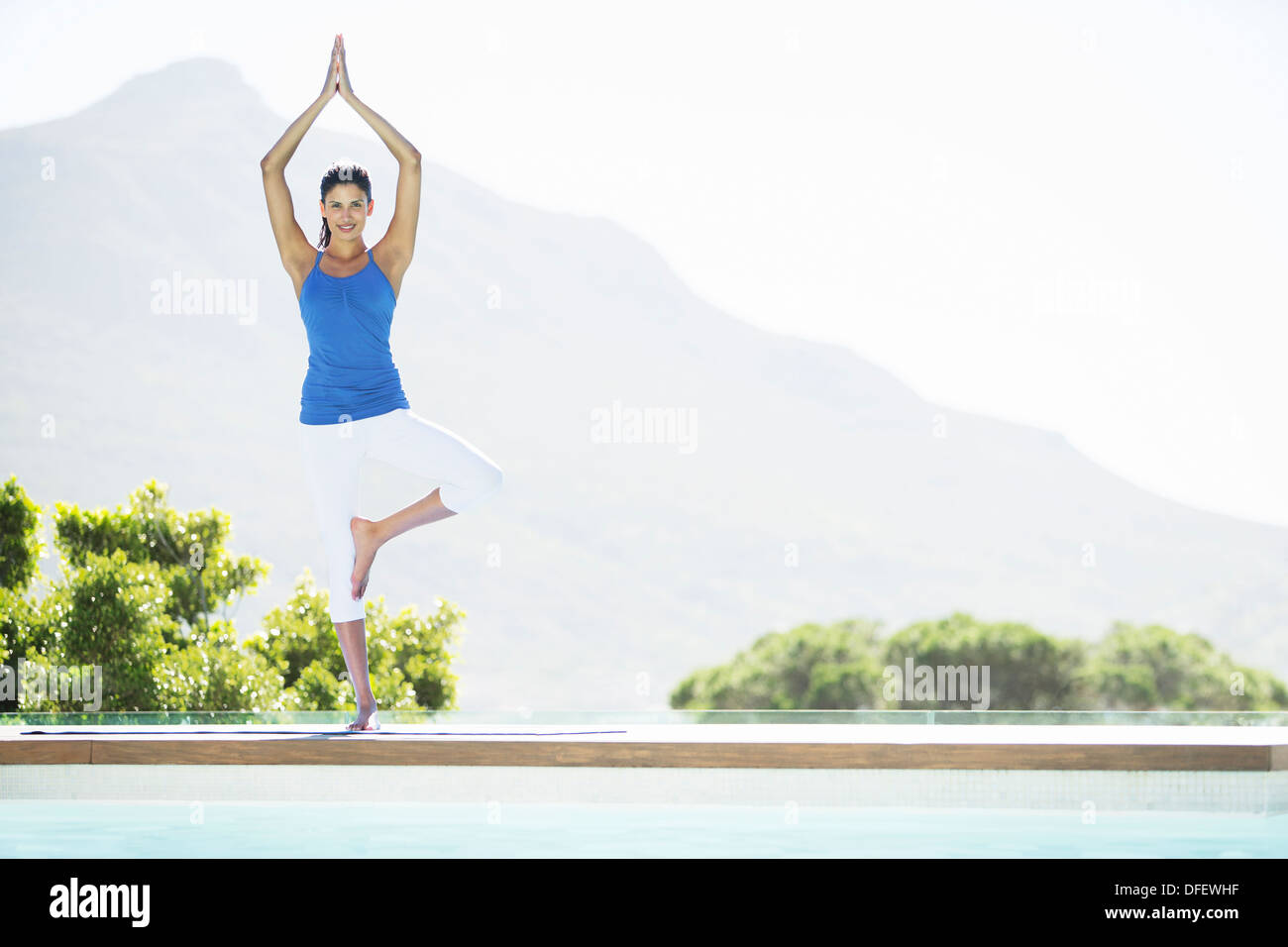 Woman practicing yoga at poolside Stock Photo