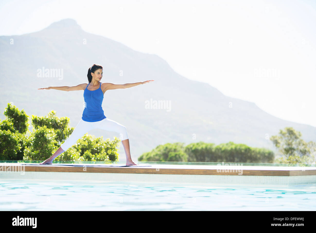 Woman practicing yoga at poolside Stock Photo