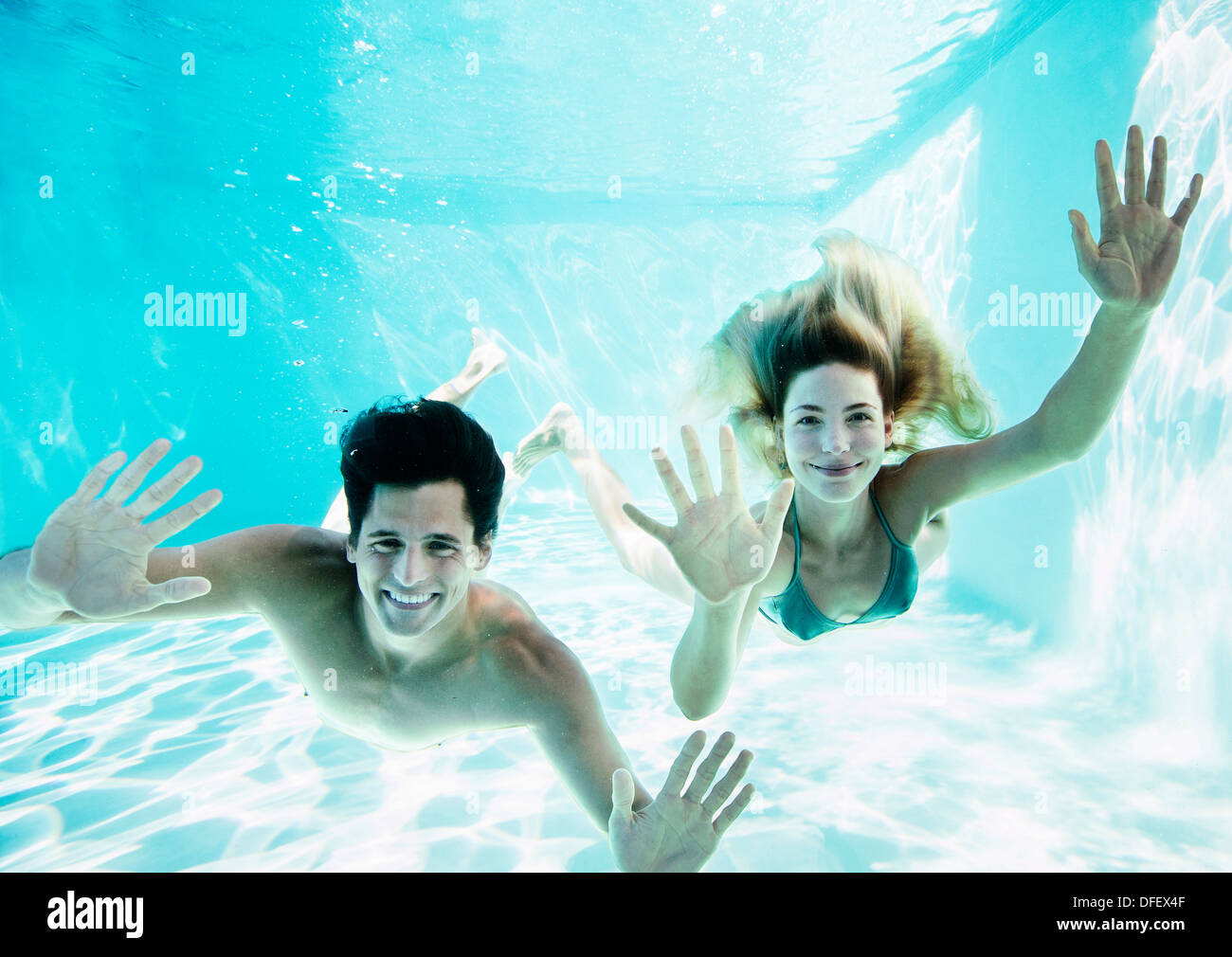 Portrait of smiling couple underwater in pool Stock Photo