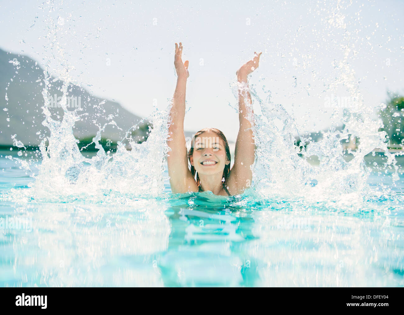 Woman splashing in swimming pool Stock Photo