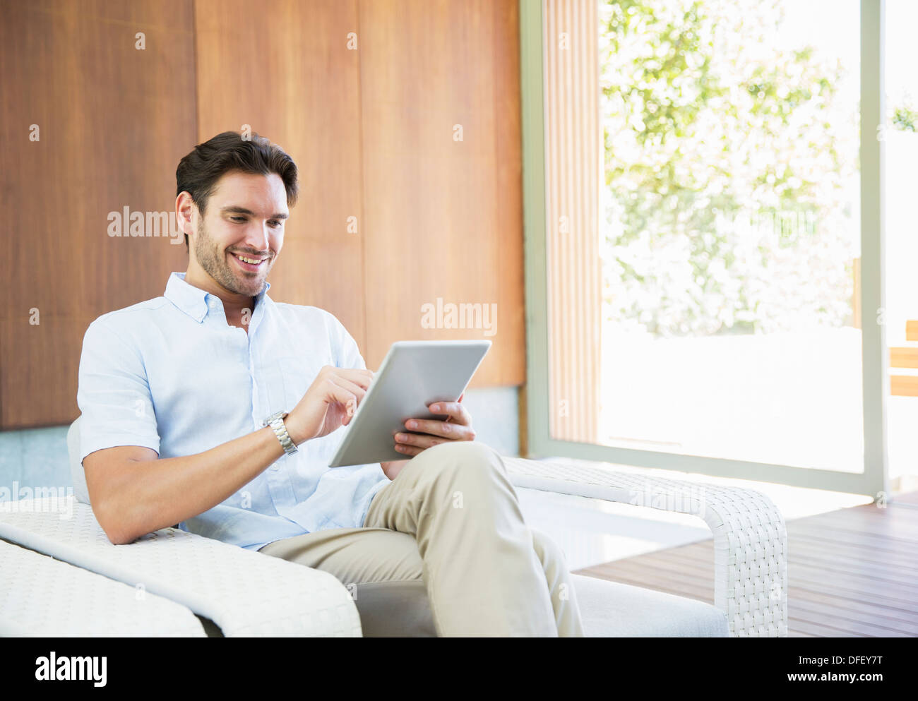 Man using digital tablet in armchair Stock Photo