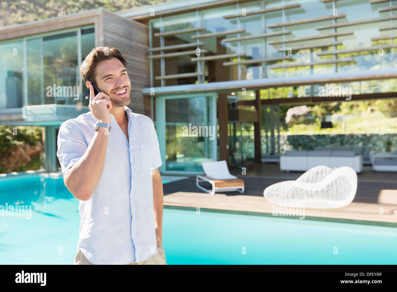 Man talking on cell phone at poolside Stock Photo