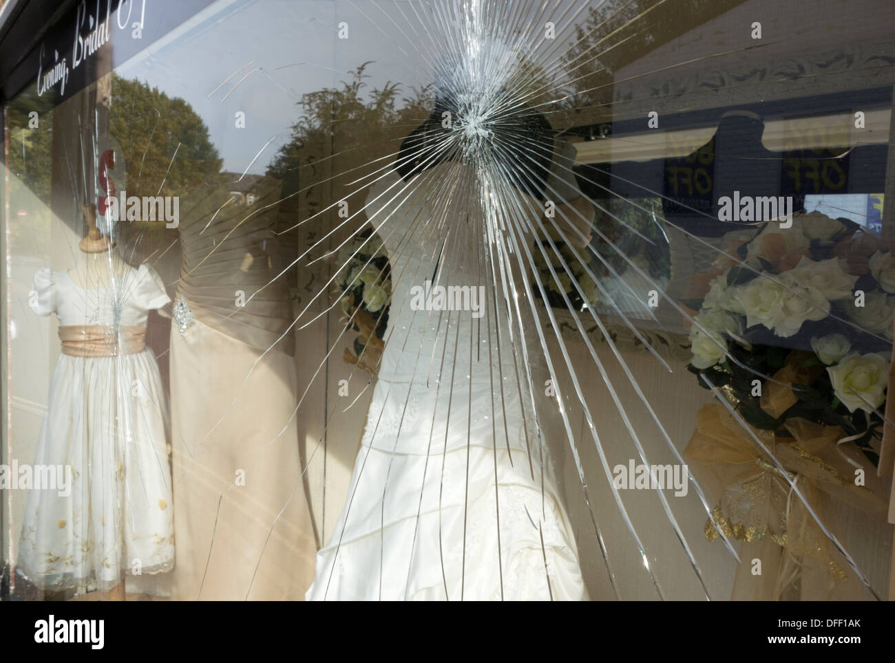 A broken vandelised window of a shop selling wedding dresses. Stock Photo