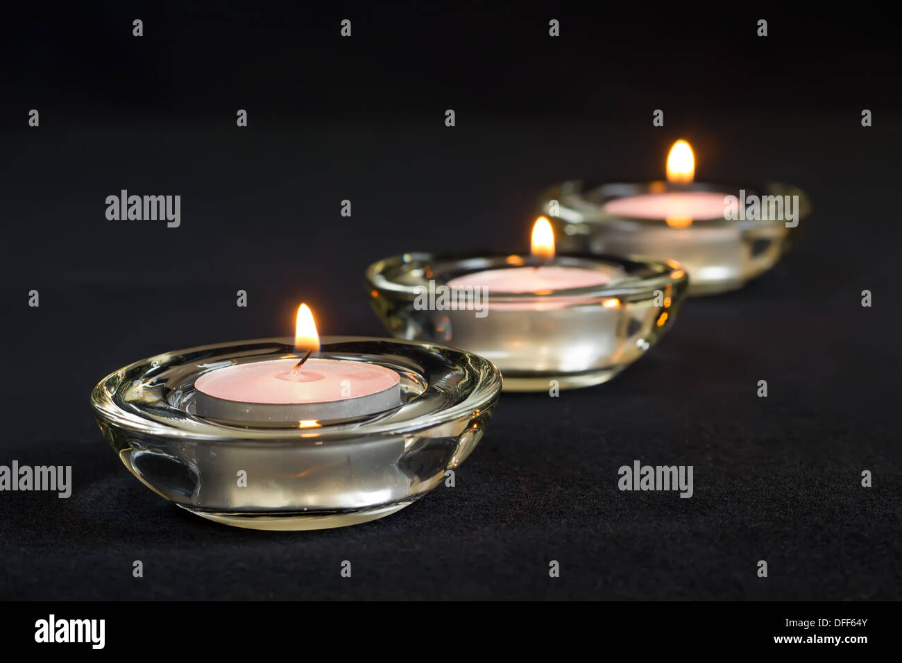 Three burning candles on black background Stock Photo - Alamy