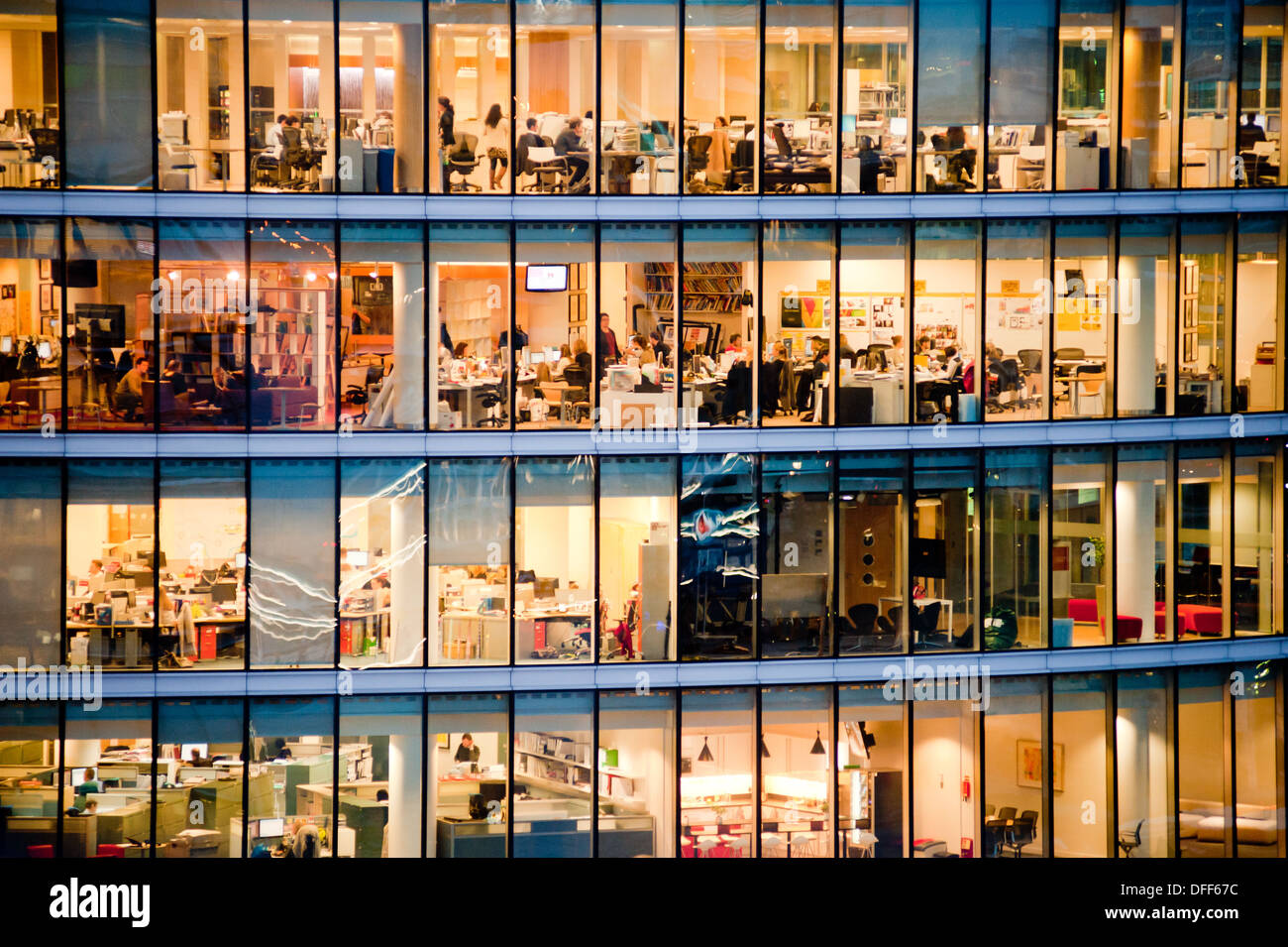 London, UK - February 2013: people work in a modern office building at dusk. Stock Photo