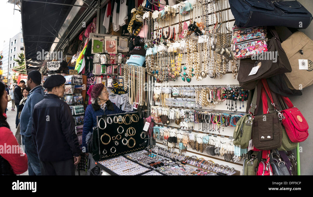 elderly Chinese lady & relative shop at a small Chinatown novelty boutique with sidewalk display of jewelry handbags novelties Stock Photo