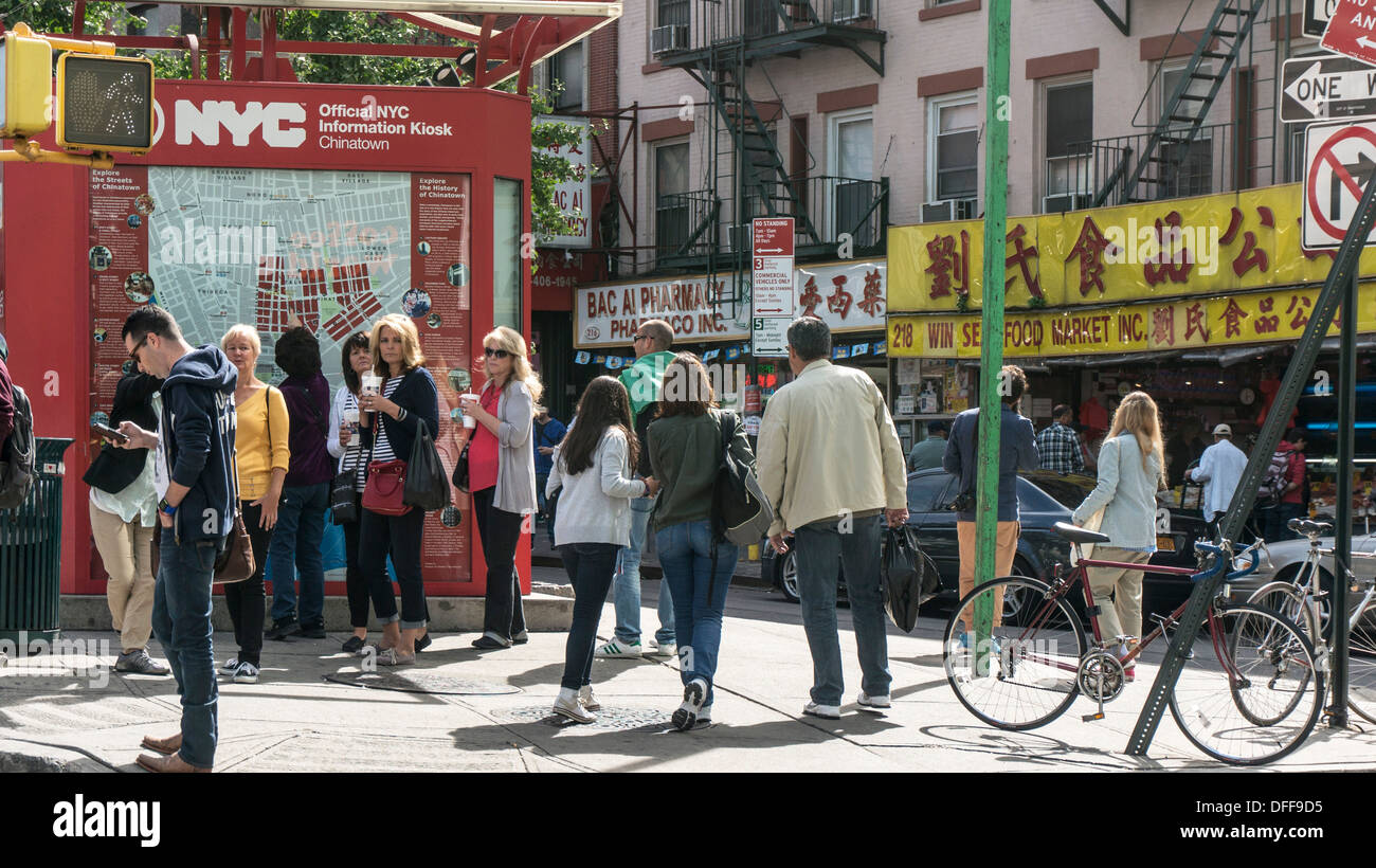 groups of tourists cluster around official NYC Chinatown Information kiosk to get their bearings before exploring area Manhattan Stock Photo