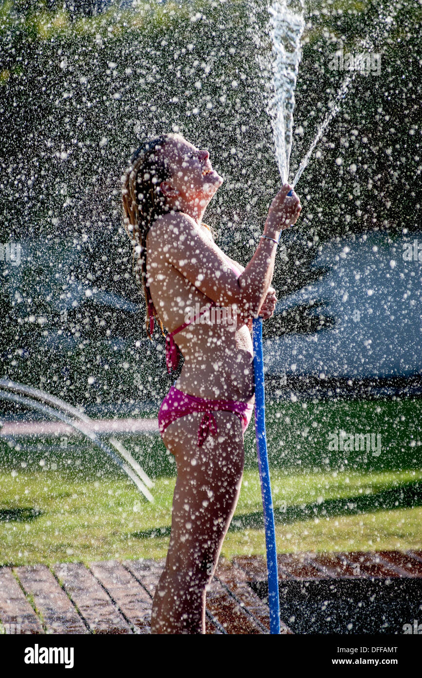 A girl in a pink bikini sprays water from a hose Stock Photo - Alamy