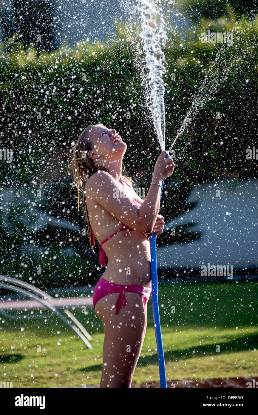 A girl in a pink bikini sprays water from a hose Stock Photo - Alamy