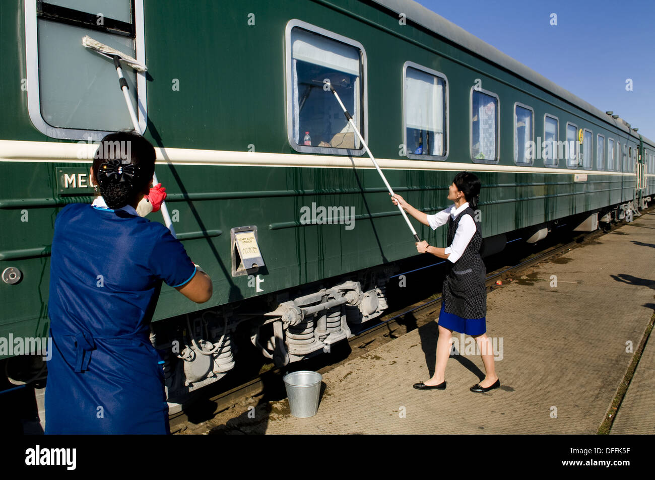 Mongolian train personel wash the train´s window at a Mongolian railway stop Stock Photo