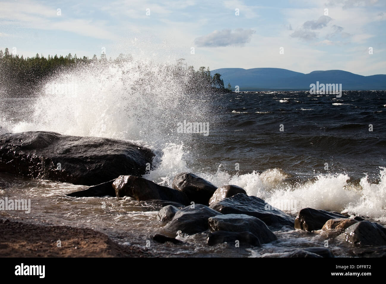 big wave with white foam splashes on stone sea shore background Stock Photo