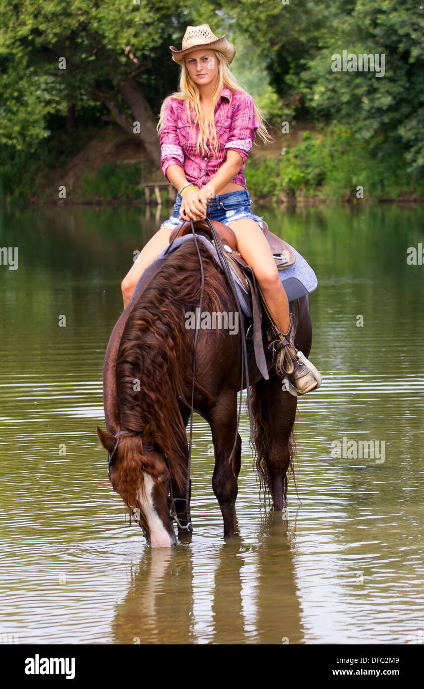 Cowgirl on a horse in the river, drinking the water. Stock Photo