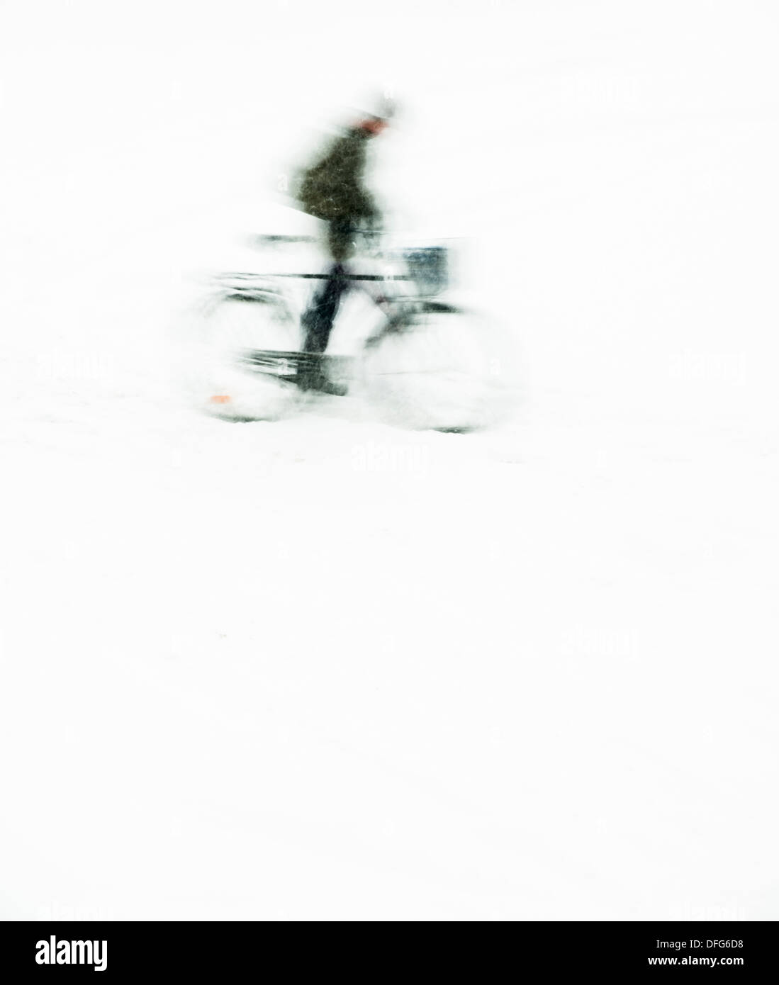 Silhouette with blurred motion of man riding a bike in snowfall with  room for copyspace Stock Photo