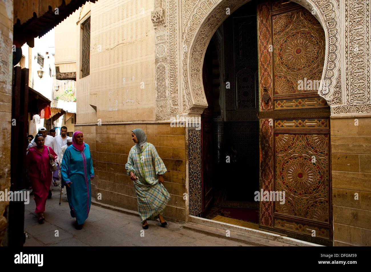 Muslim women walking in a street near one of the entrance of the Sidi Ahmed Tijani mosque ( Morocco) Stock Photo