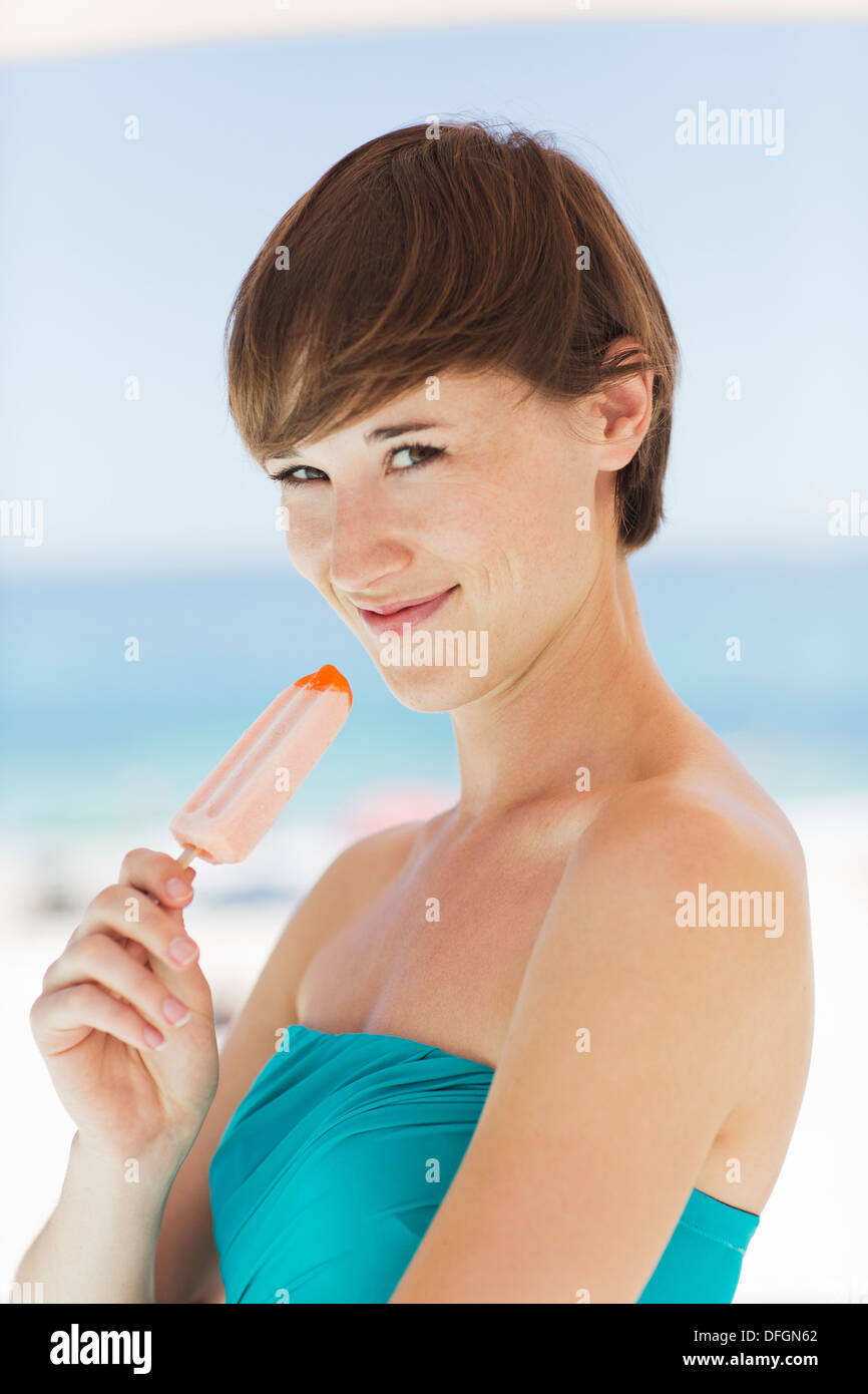 Woman eating flavored ice on beach Stock Photo