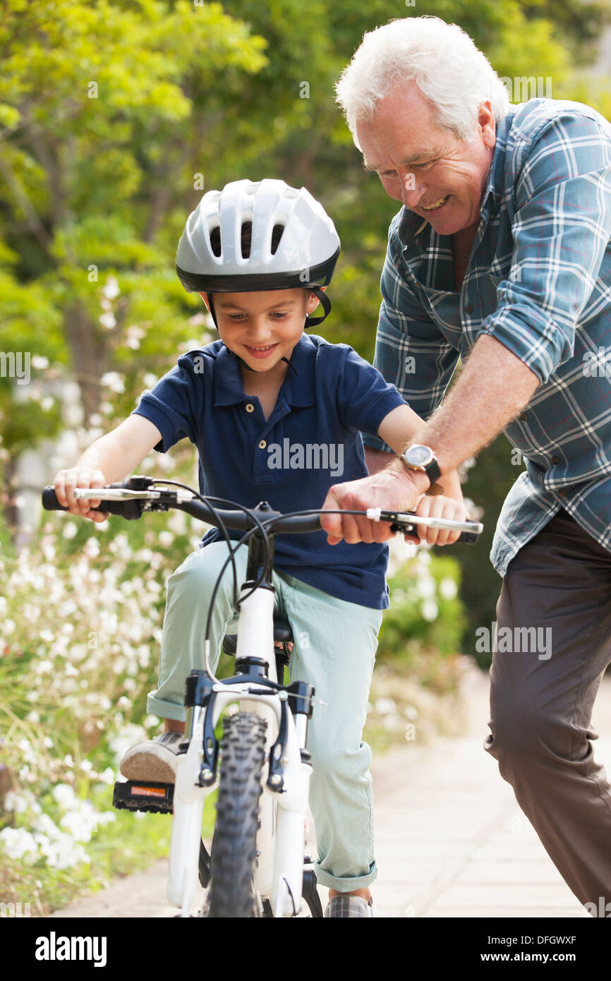 Grandfather teaching grandson to ride bicycle Stock Photo