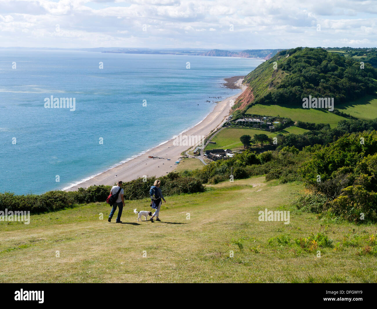 Two walkers and a dog on the South West coast path at Branscombe Devon England Stock Photo
