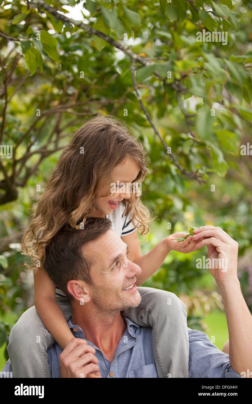 Father carrying daughter on shoulders outdoors Stock Photo