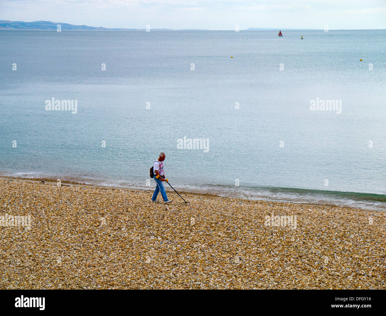 A man using a metal detector on Lyme Regis Beach, Dorset, England Stock