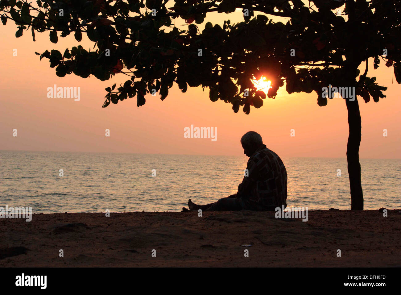 ISOLATED... The picture shows an old man as a silhoutte in the dusk.  The feeling of loneliness is clear in his gesture Stock Photo