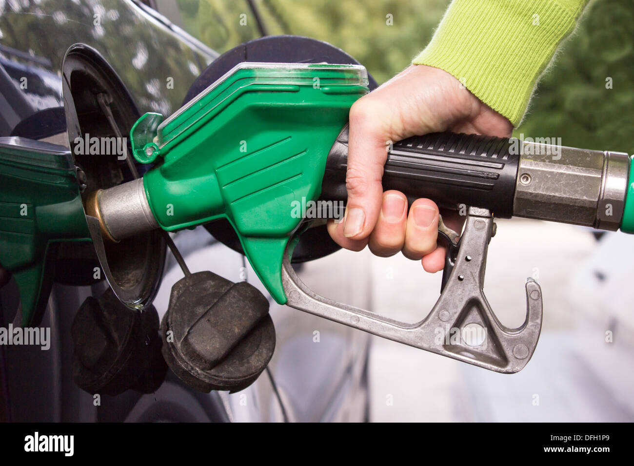 Female hand with pistol grip filling car tank with gasoline Stock Photo