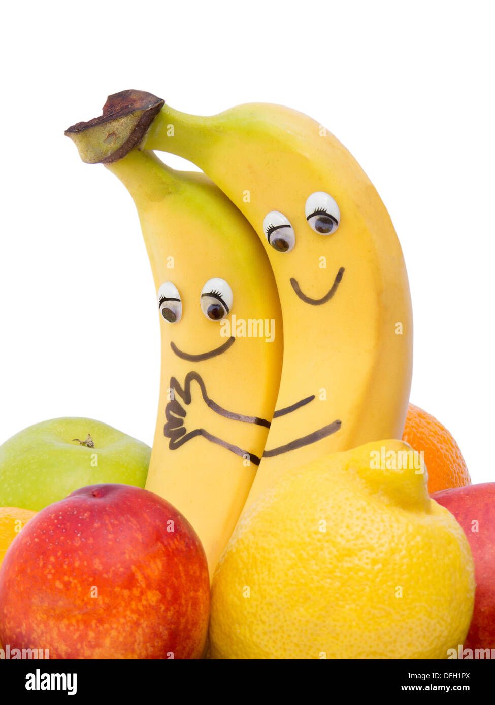 Two loving bananas with eyes and mouth between other fruit Stock Photo