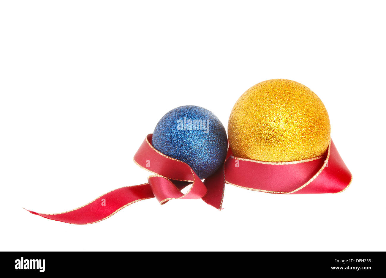 Christmas decoration of blue and gold glitter baubles entwined with a gold edged red ribbon isolated against white Stock Photo