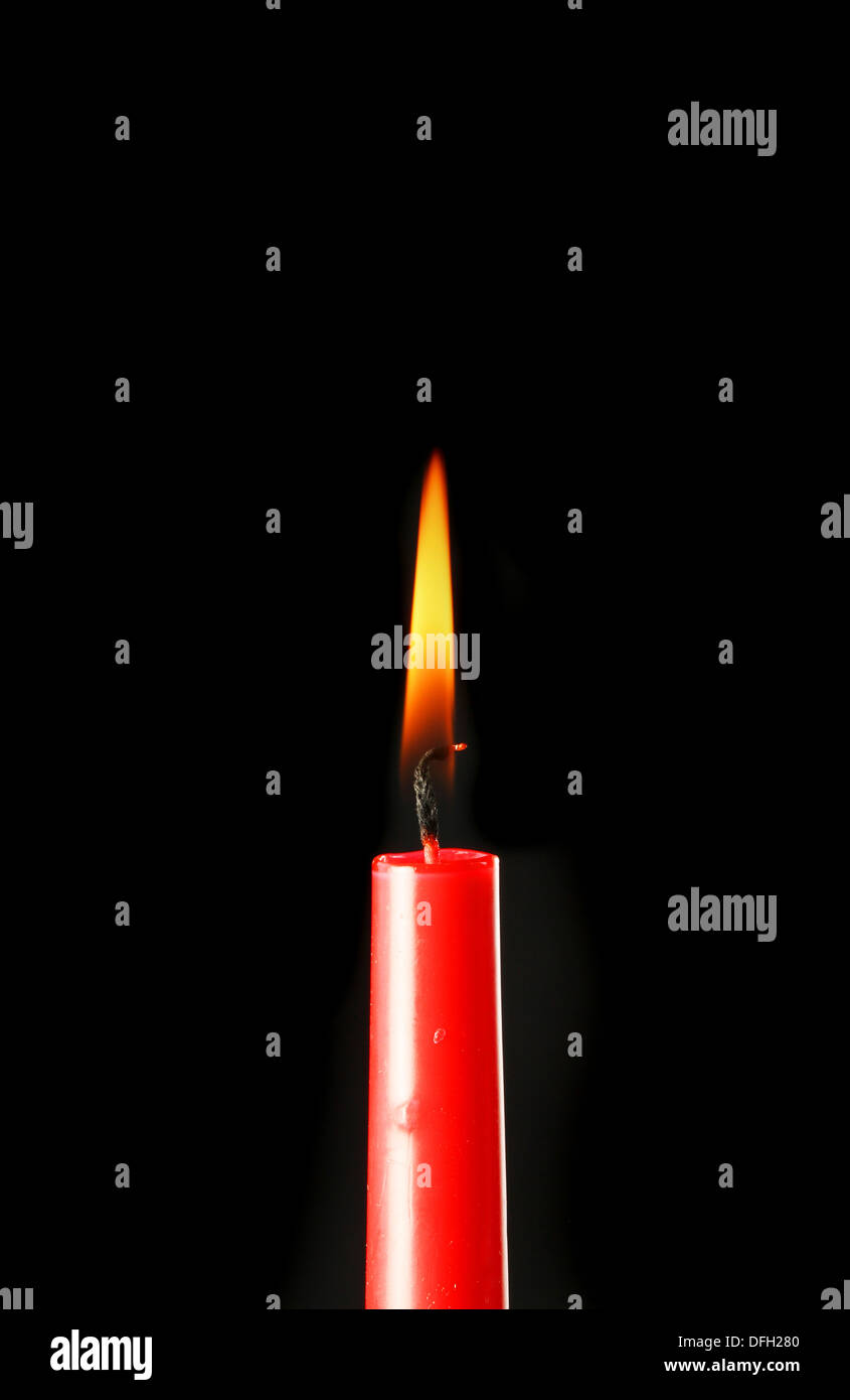 Burning red candle against a black background Stock Photo