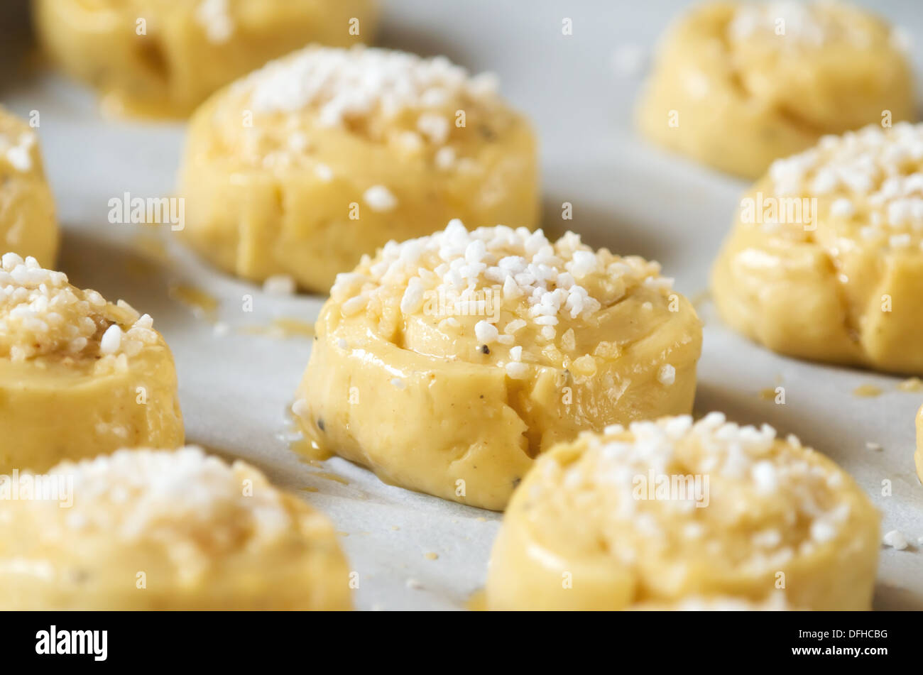 Raw sweet buns or bread rolls on a baking sheet with parchment ready for the oven Stock Photo
