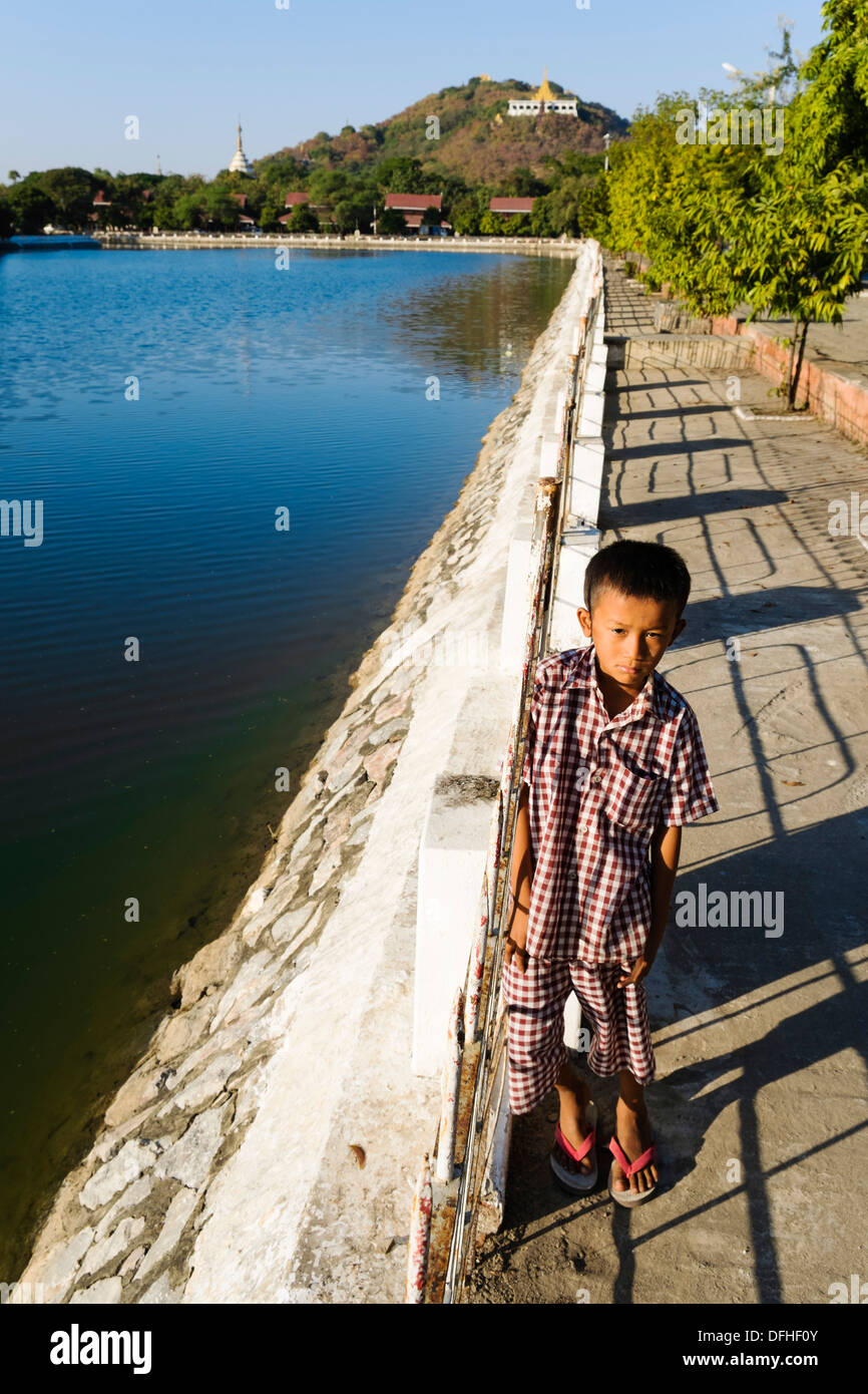 Boy standing at the canal at the Royal Palace in front of Mandalay Hill, Mandalay, Myanmar, Asia Stock Photo